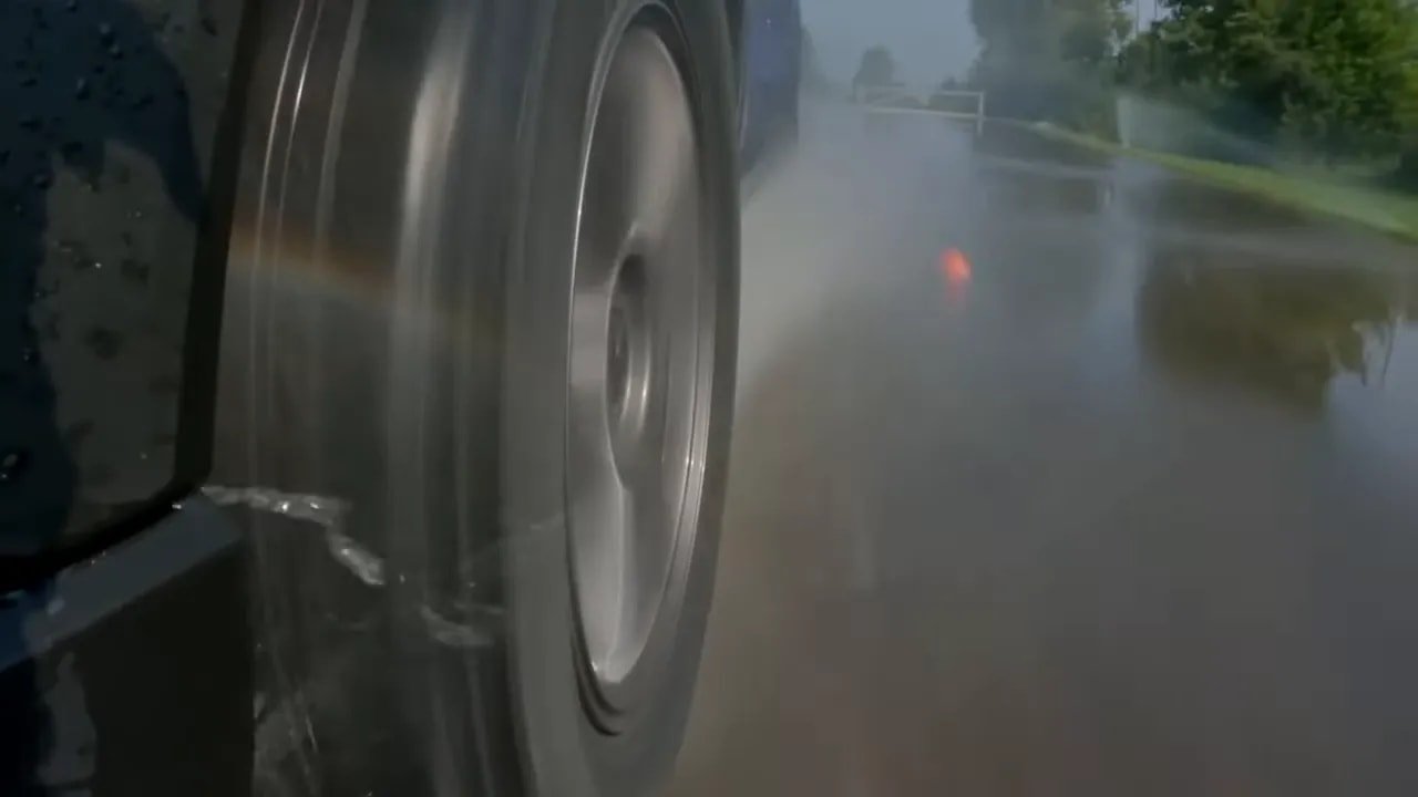 All-season tire running on wet pavement with spray visible