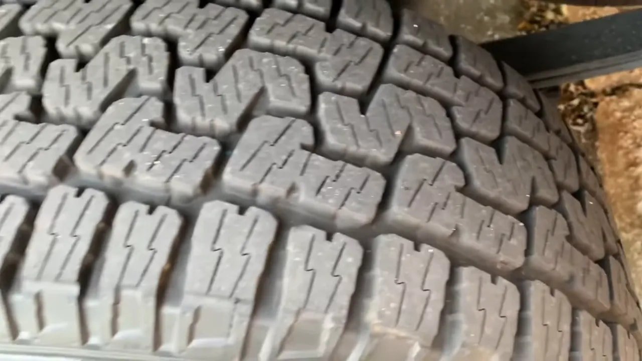 Detailed close-up of all-terrain tire tread blocks and sipes for reduced road noise
