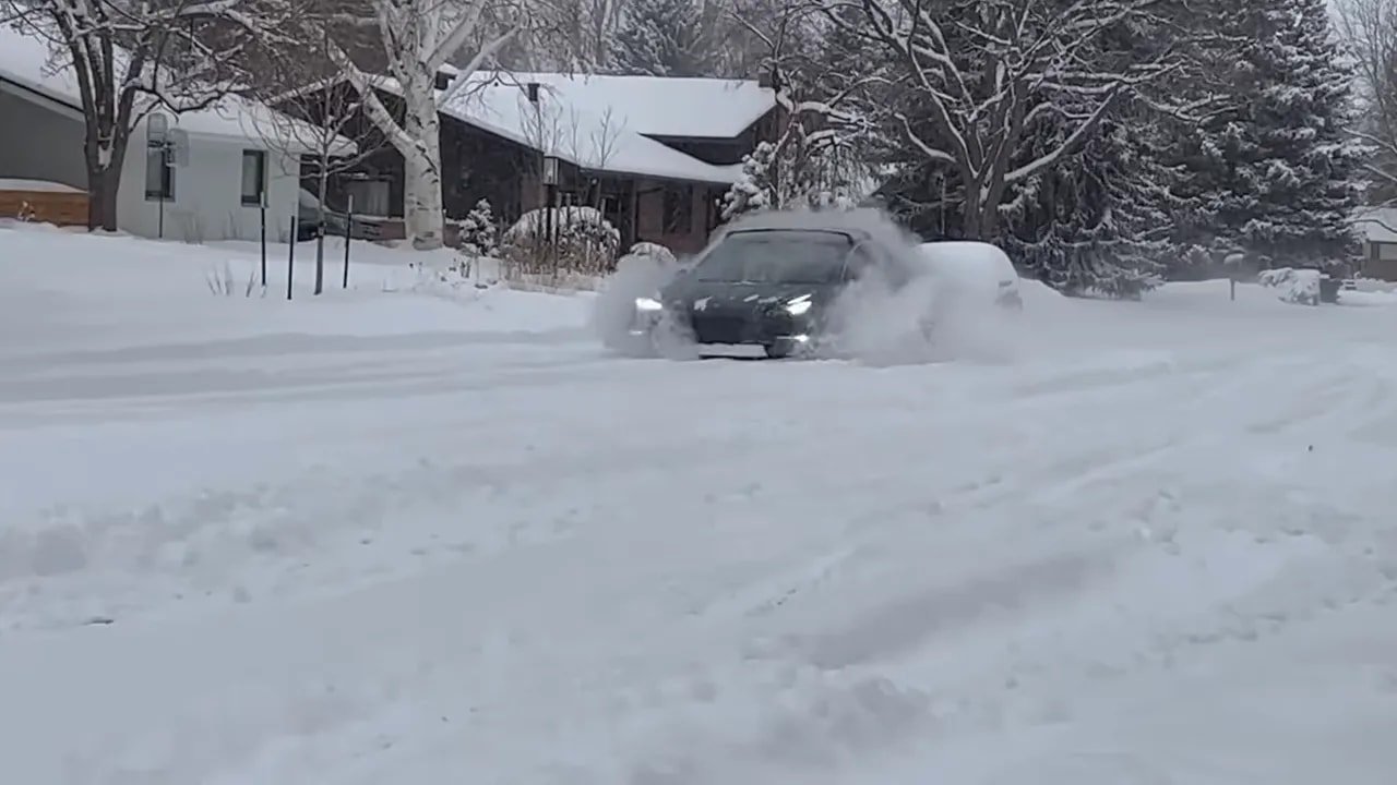 Car moving through snow in a winter neighborhood setting