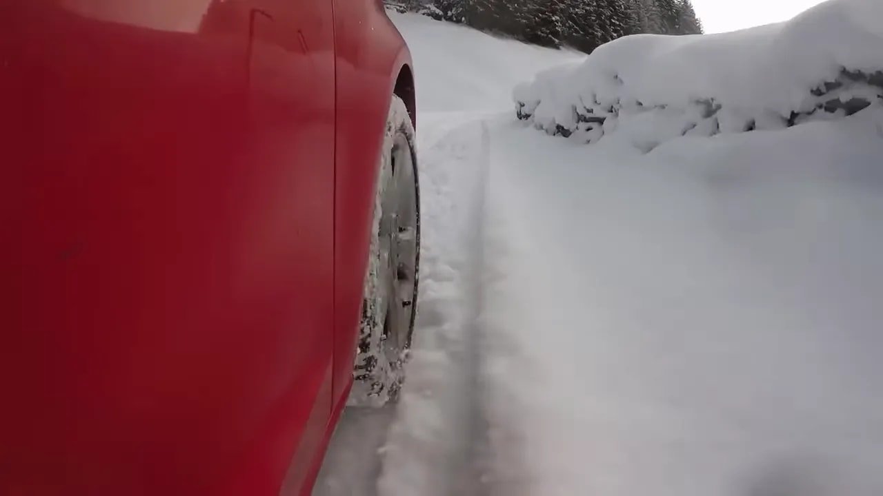 Car tire rolling through snowy road with visible tread blocks