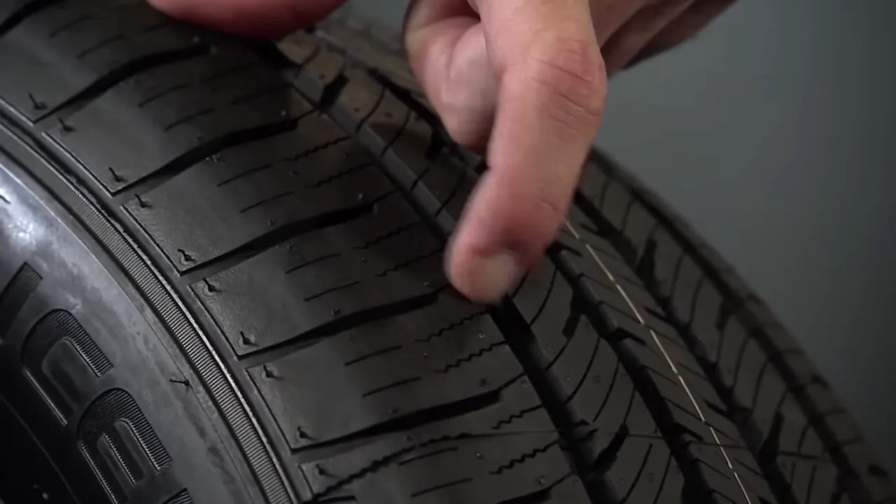 Close-up view of an all-season tire tread with grooves and sipes