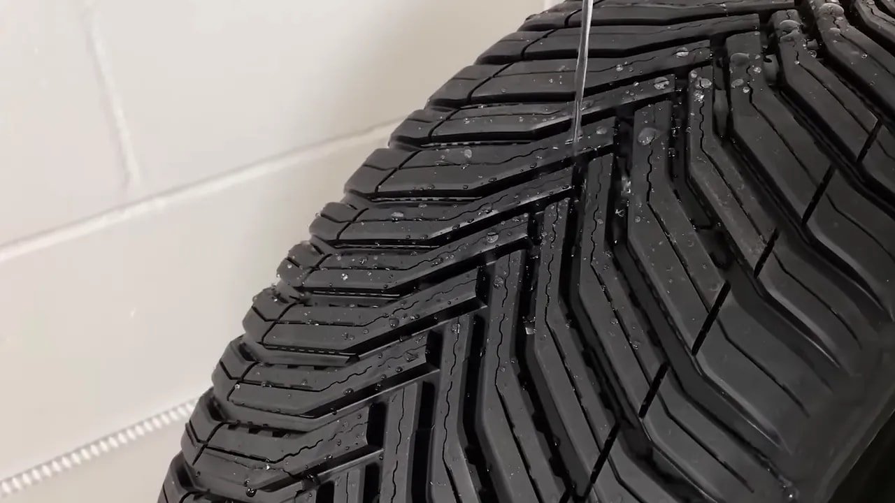 Close-up of all-season tire tread with water spray on a tire test rig