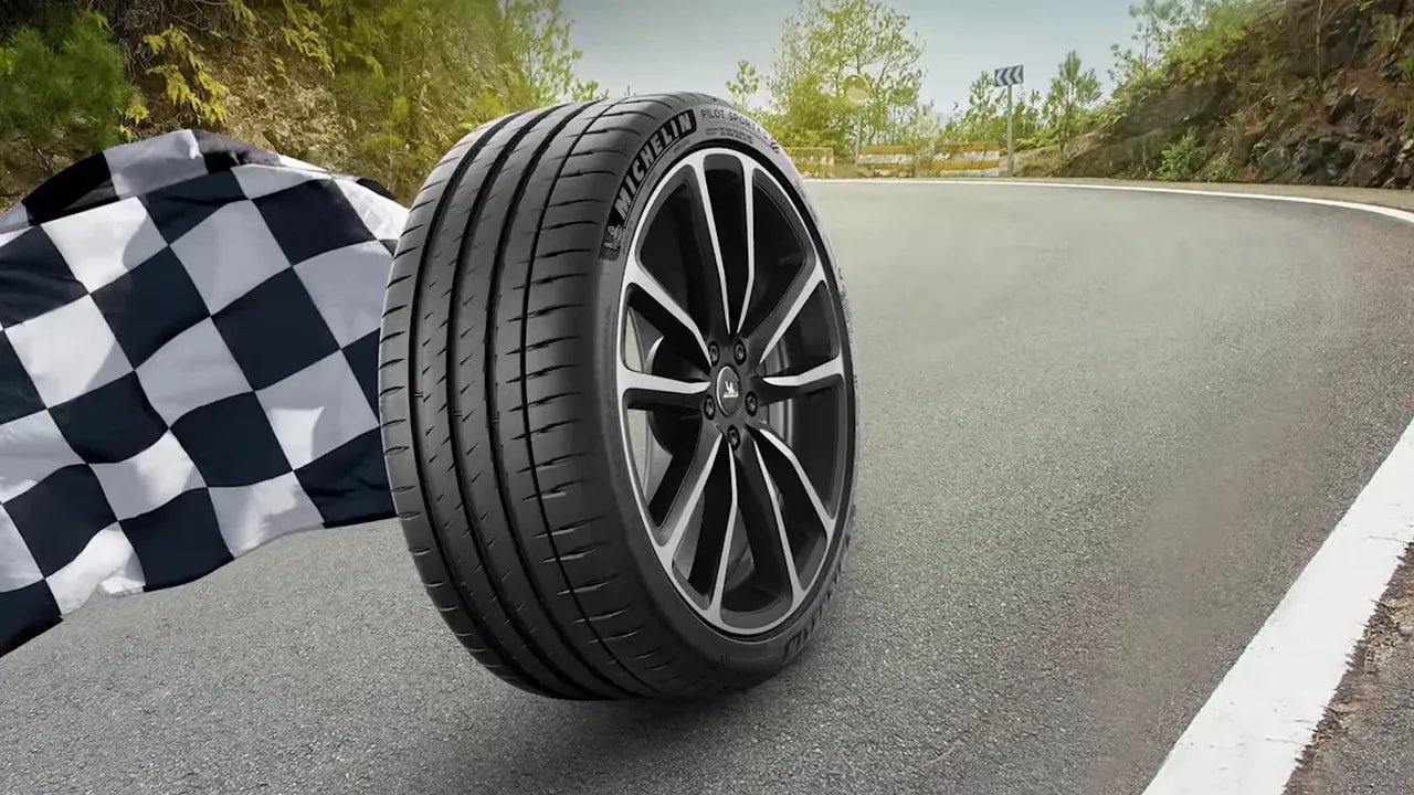 Michelin Pilot Sport 4S UHP summer tire rolling on a paved road near a checkered flag backdrop
