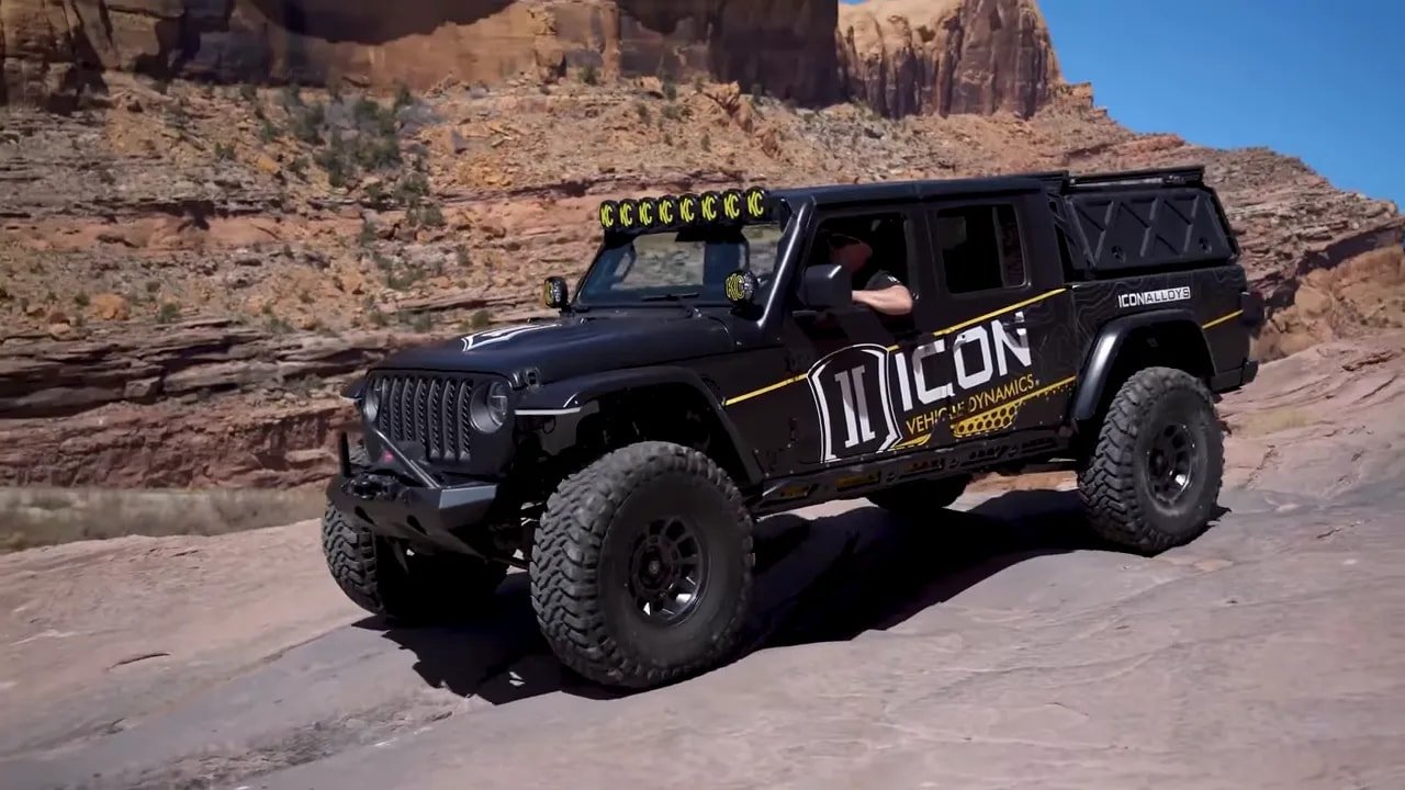 Mud-terrain tire equipped Jeep climbing rocky trail in desert terrain