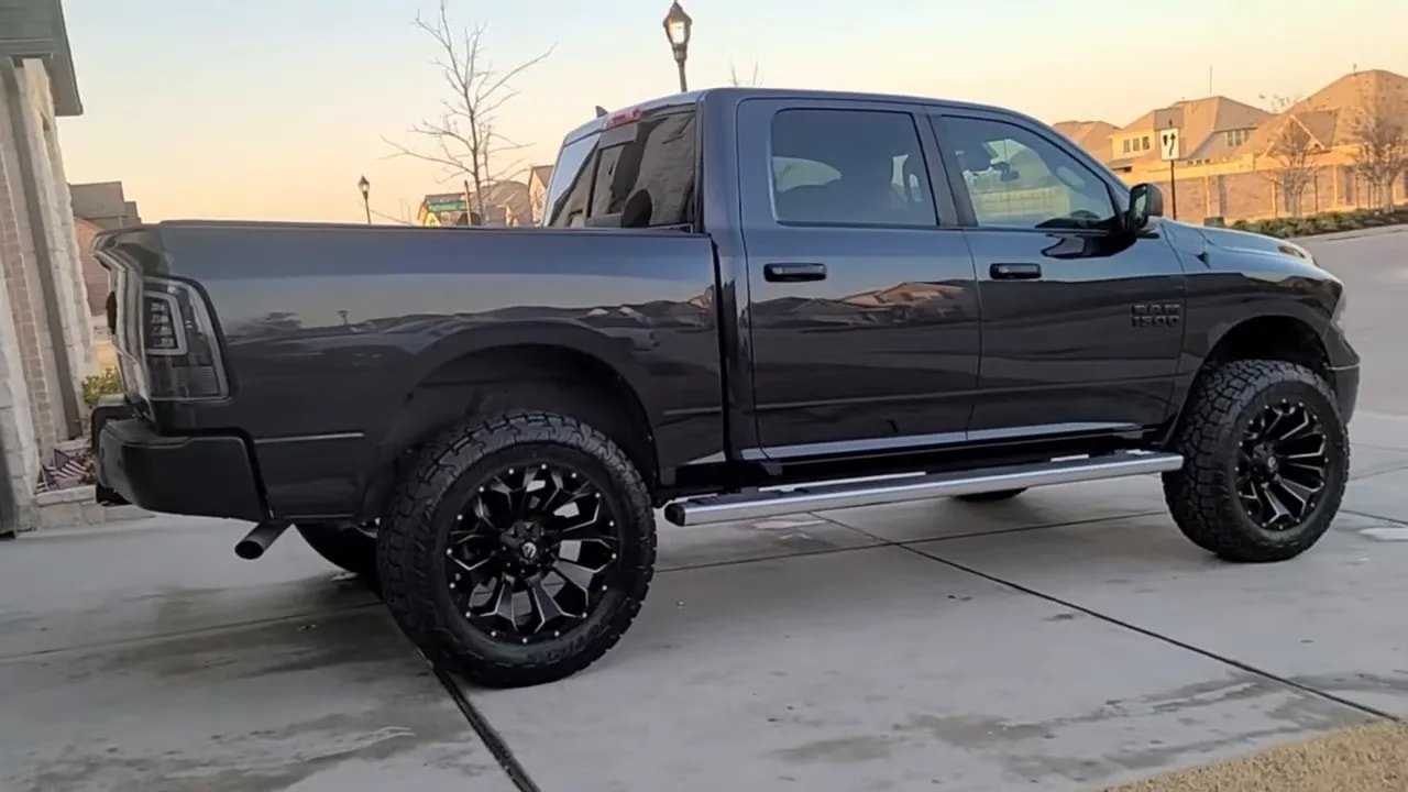 Wide view of a pickup truck with all-terrain tires parked at home