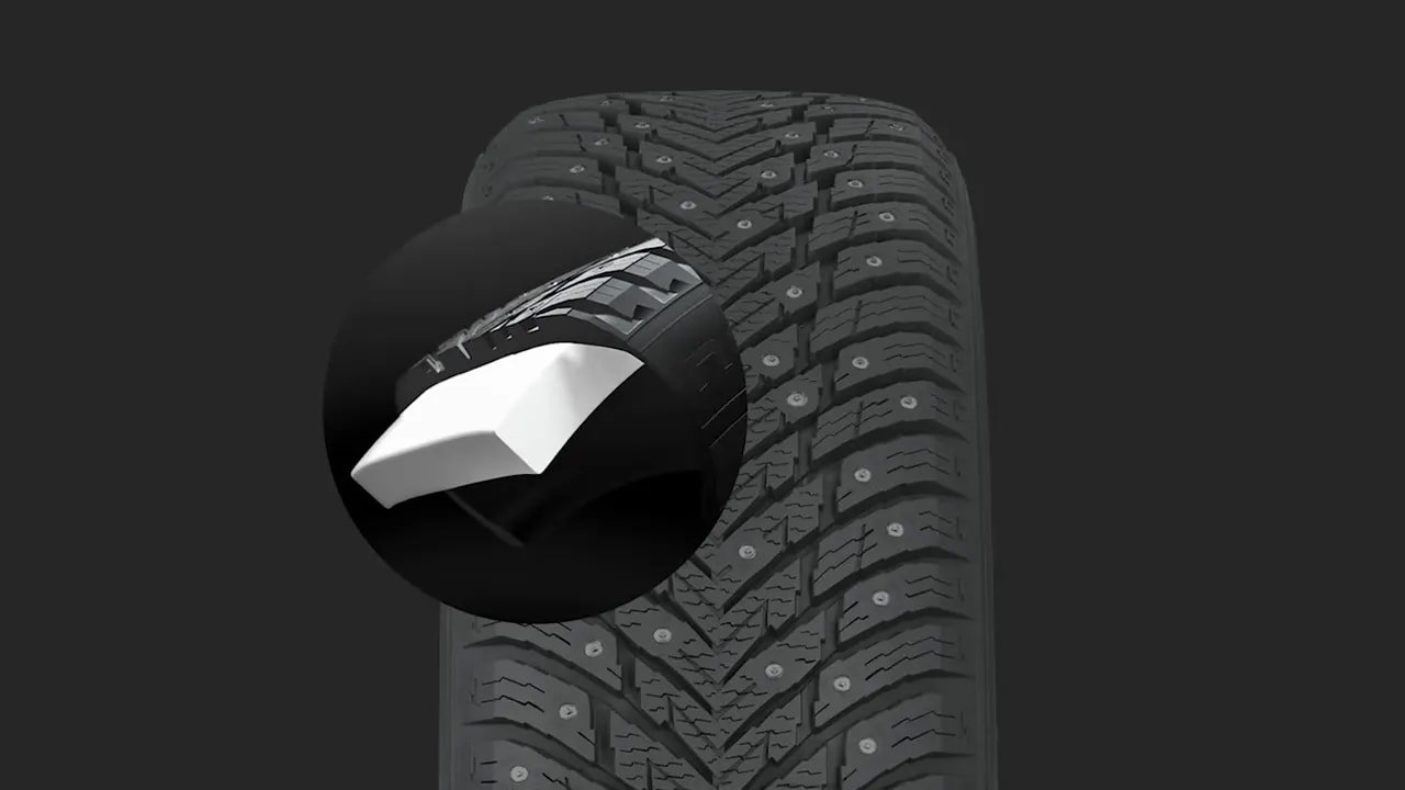 Studded winter tire tread close-up showing tread blocks and metal studs