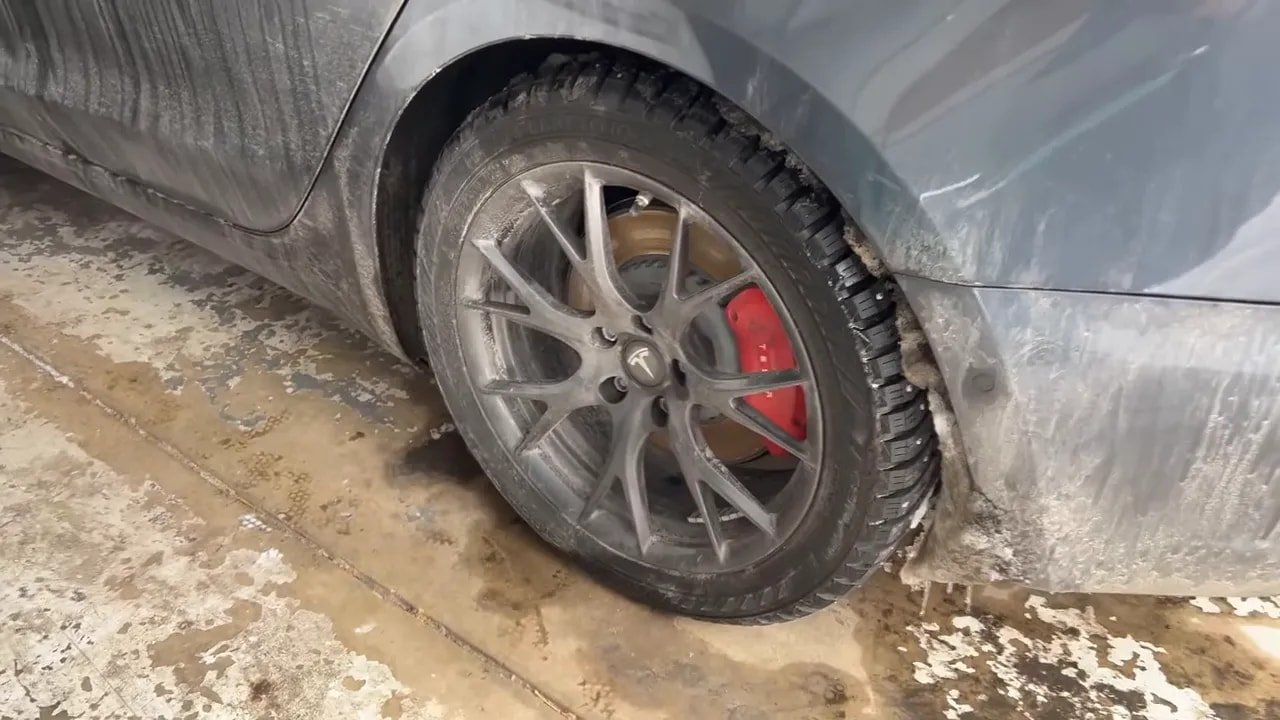 Vehicle wheel with studded winter tire on icy slushy road