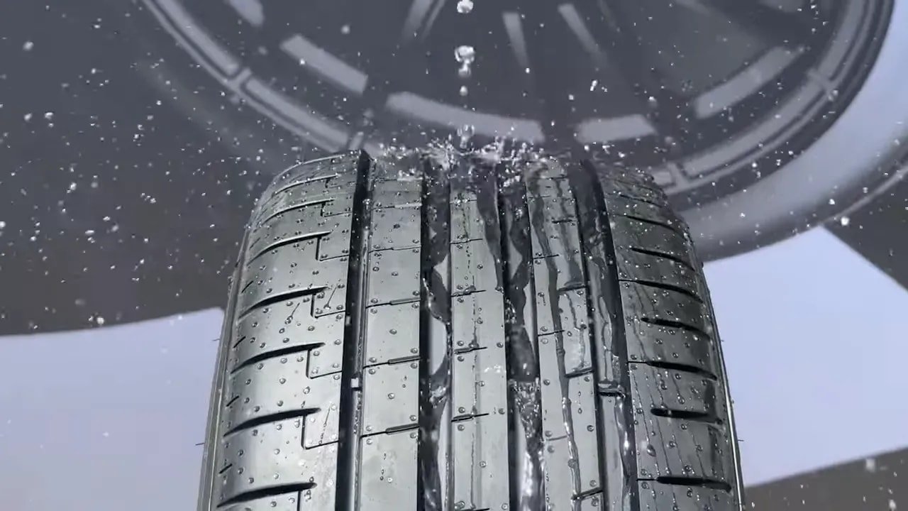 Close-up of a summer tire tread with water droplets on the wet road