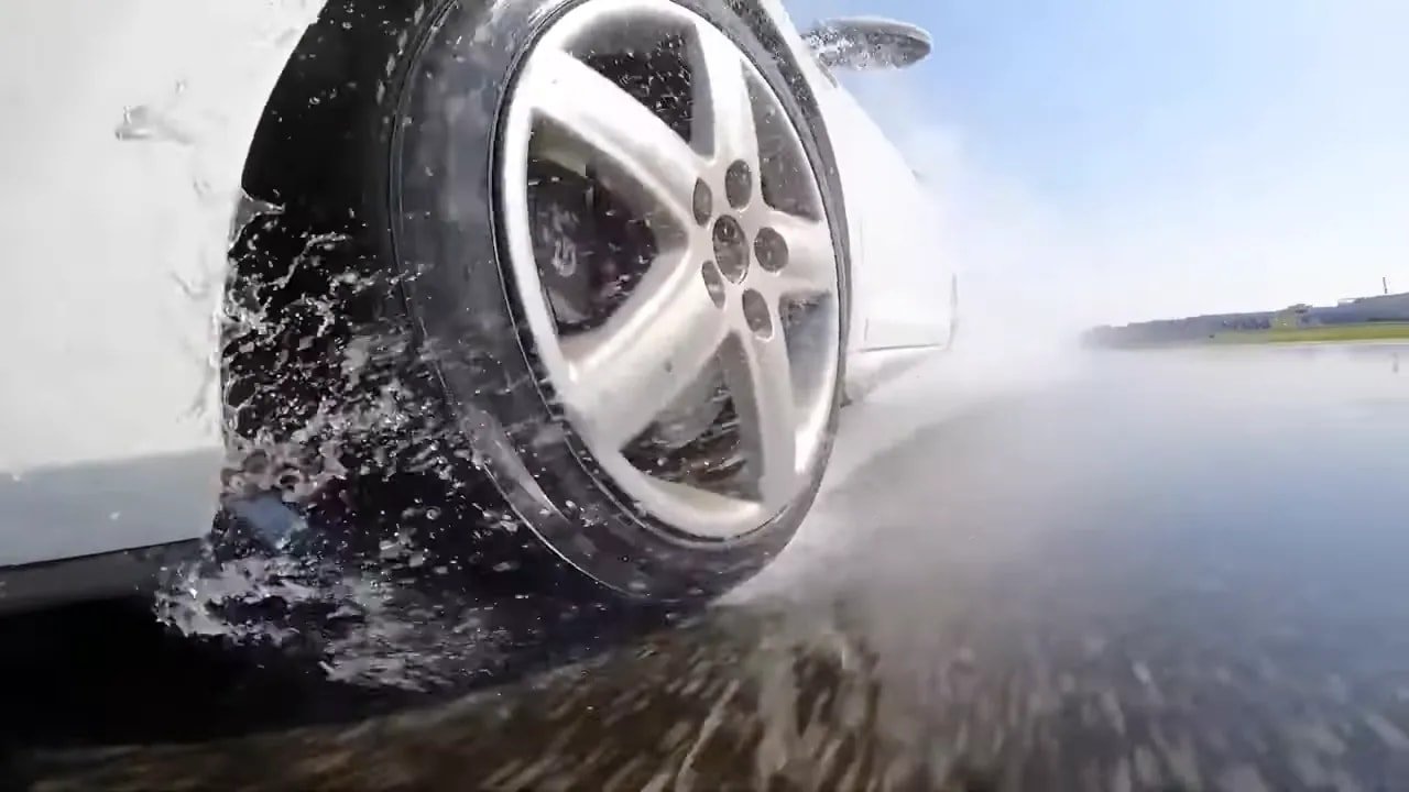 Summer tire creating water spray during a wet road test