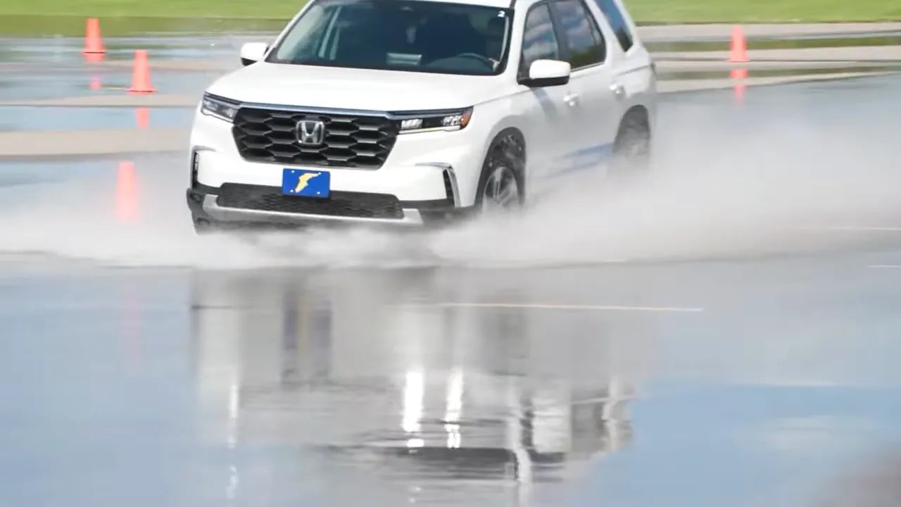SUV driving on wet track during all-weather tire handling test