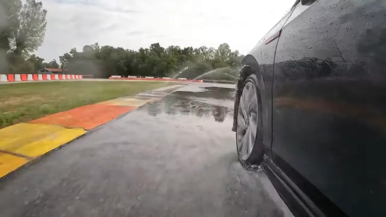 Tire on wet race track spraying water to demonstrate all-season wet grip performance
