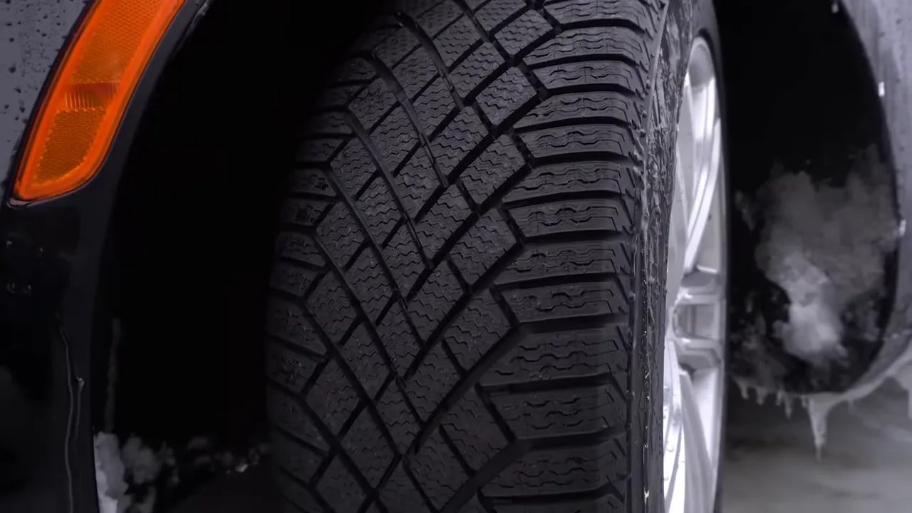 Wet-weather close-up of studless winter tire tread with tread blocks and grooves