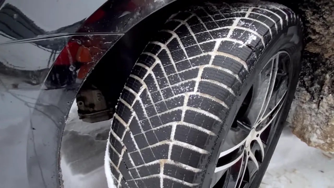 Close-up of a winter tire tread on a car driving on snowy roads